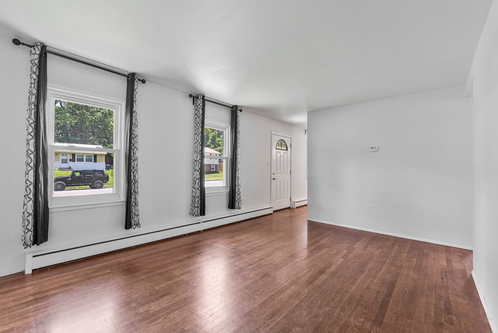 Living room with three front windows, hardwood floors and entry door