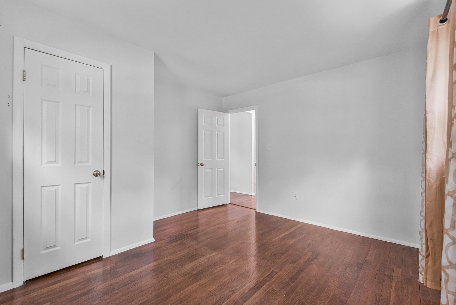 Room with hardwood floors, closet door and doorway to hallway