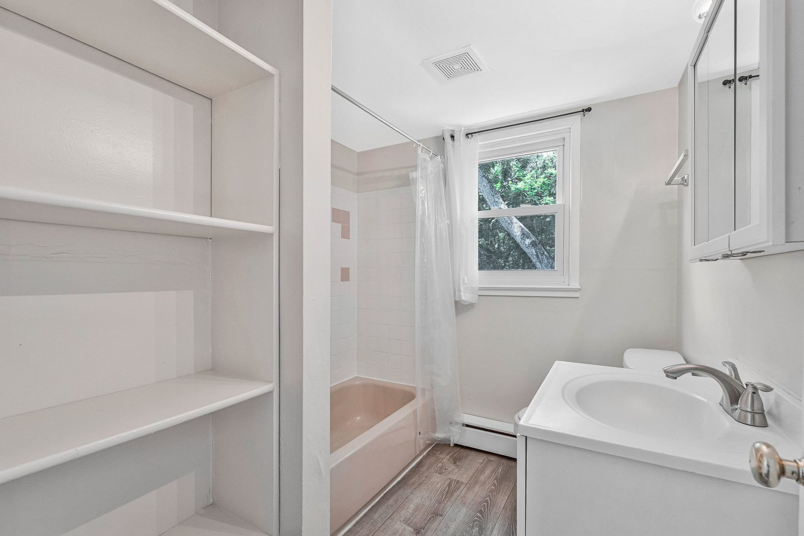 Bathroom with built-in linen shelves, tub shower and single vanity
