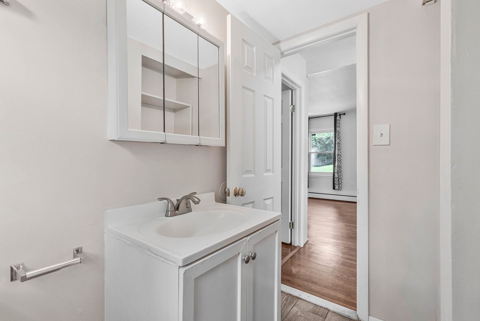 Vanity with mirrored medicine cabinet and vanity light beside open doorway