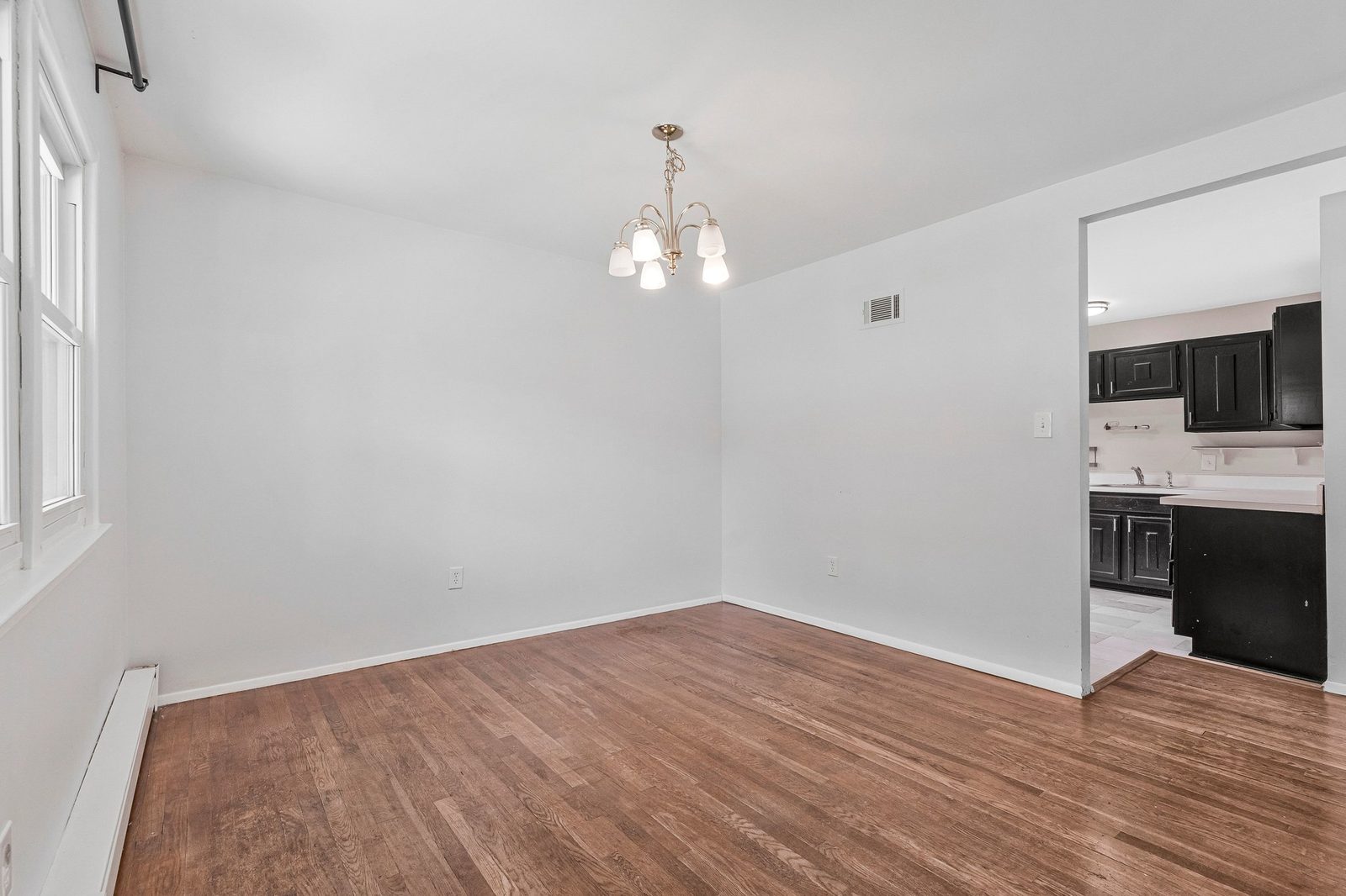 Dining area with chandelier, hardwood floors and opening to the kitchen
