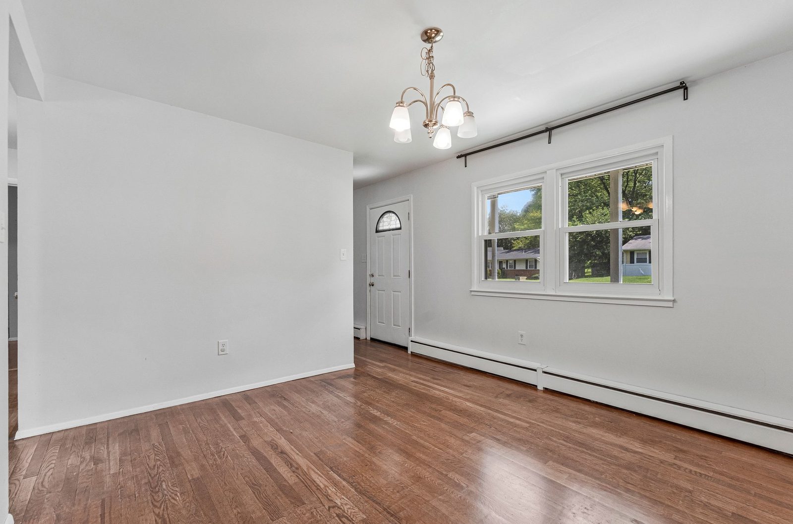 Living room with chandelier, double window and front entry door
