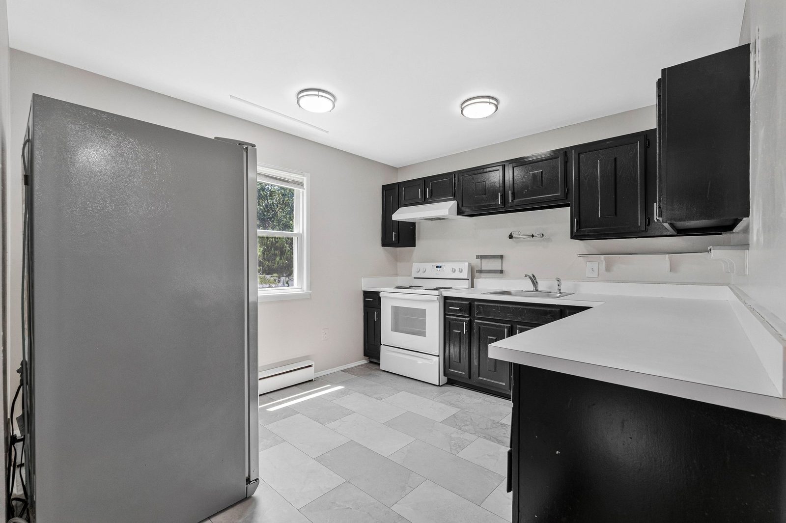 Kitchen with dark cabinets, white range, stainless refrigerator and tile floor