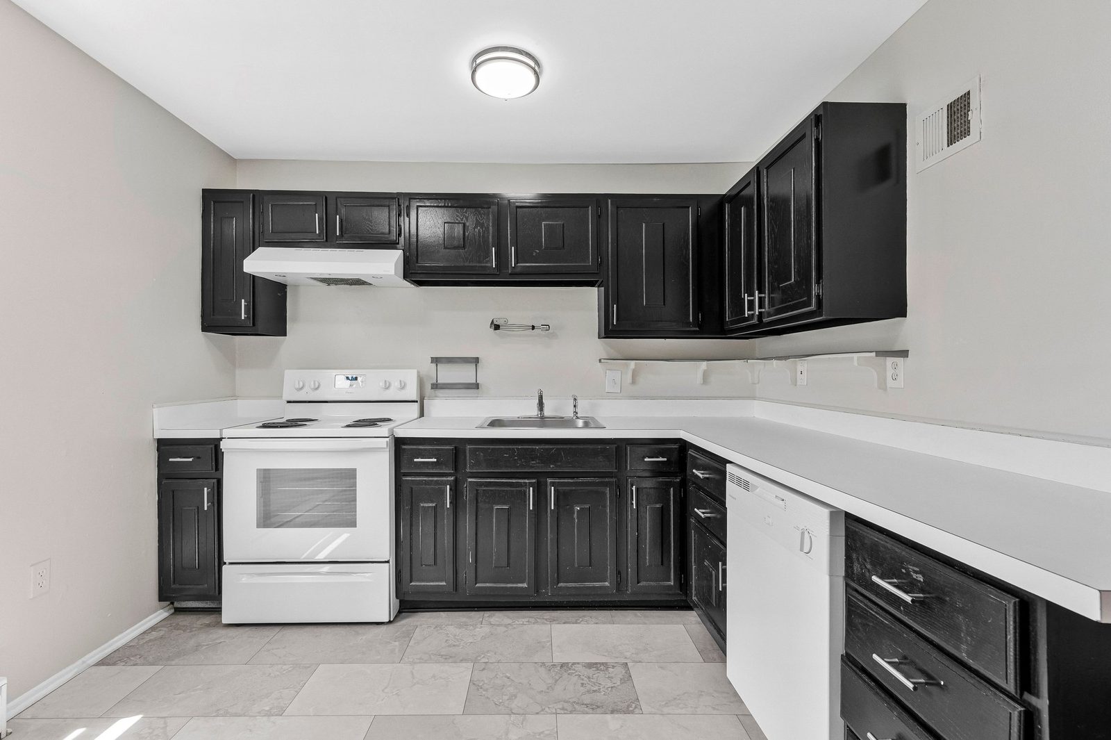 Kitchen with dark cabinets, white range, dishwasher and stainless sink
