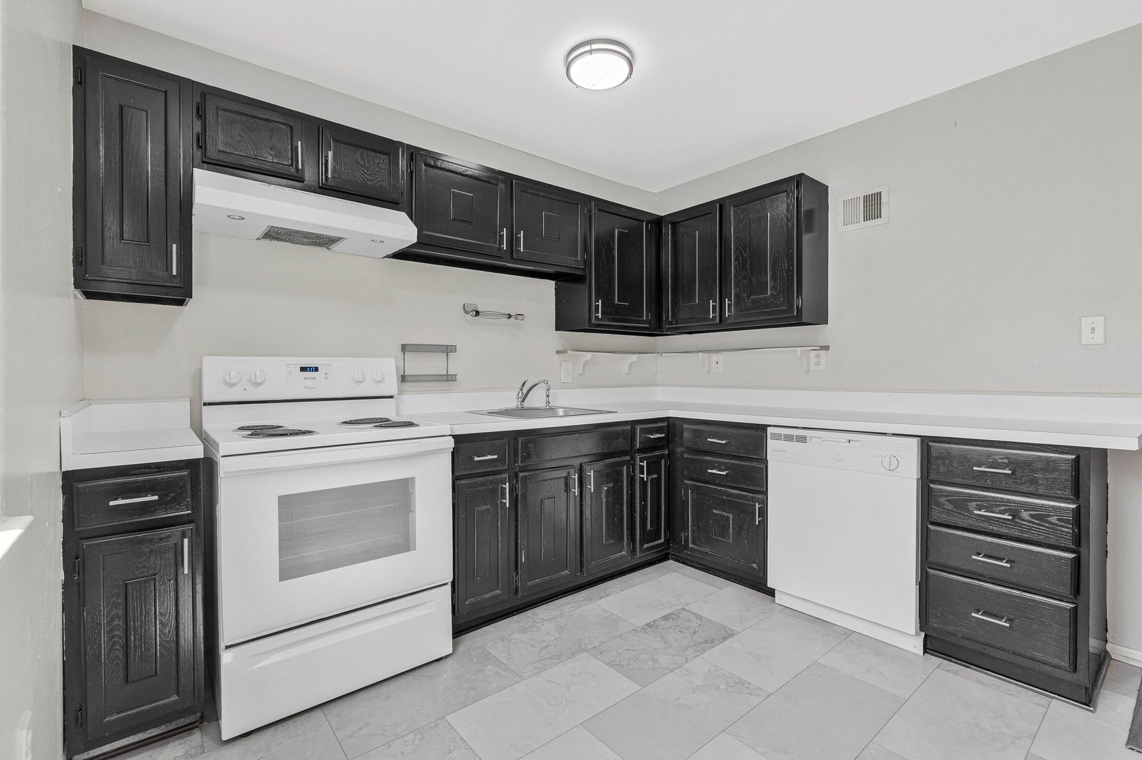 Kitchen with dark cabinets, white counters and white electric range