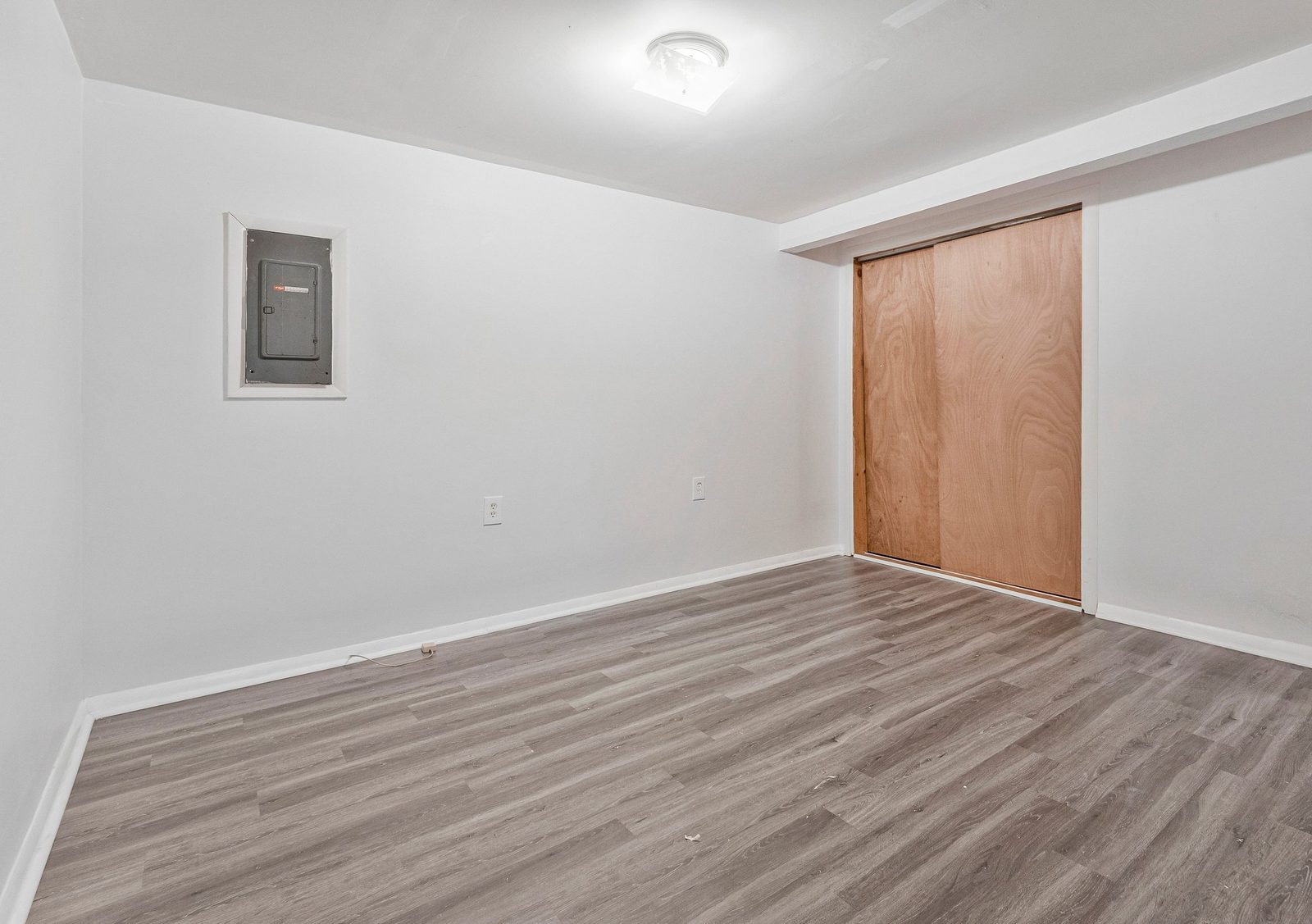 Lower-level room with plank flooring and sliding closet doors