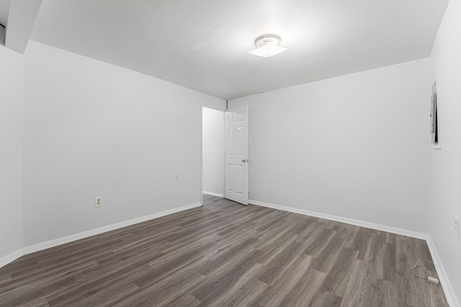 Empty room with grey plank flooring and white six-panel door