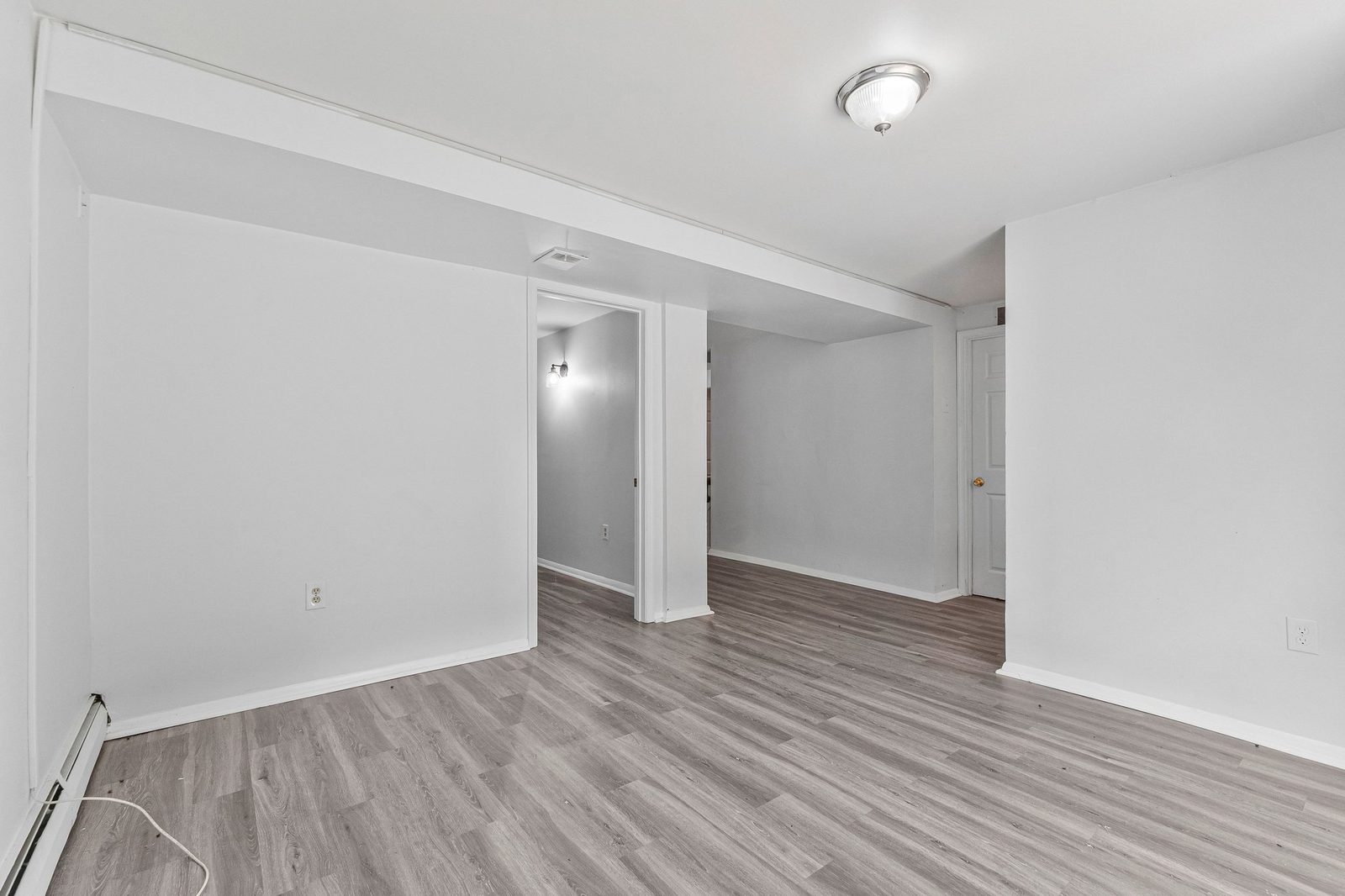 Open lower-level area with grey plank flooring and recessed doorway