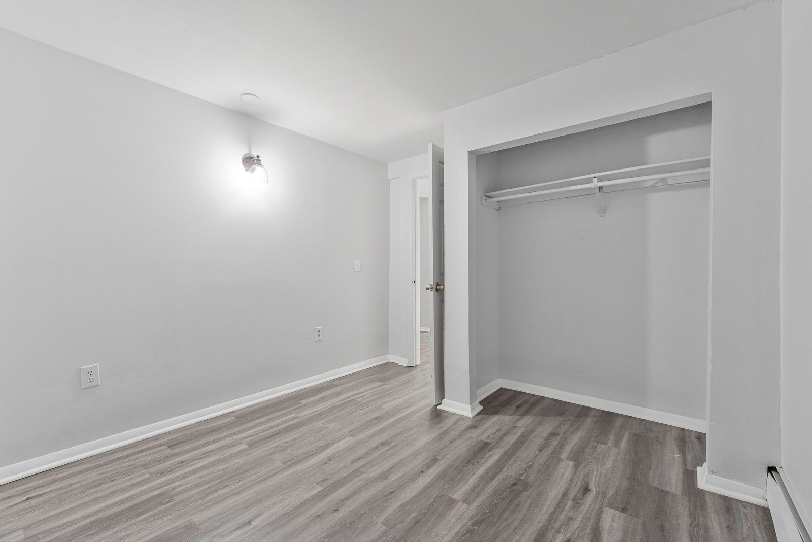 Room with open closet, hanging rod and plank flooring