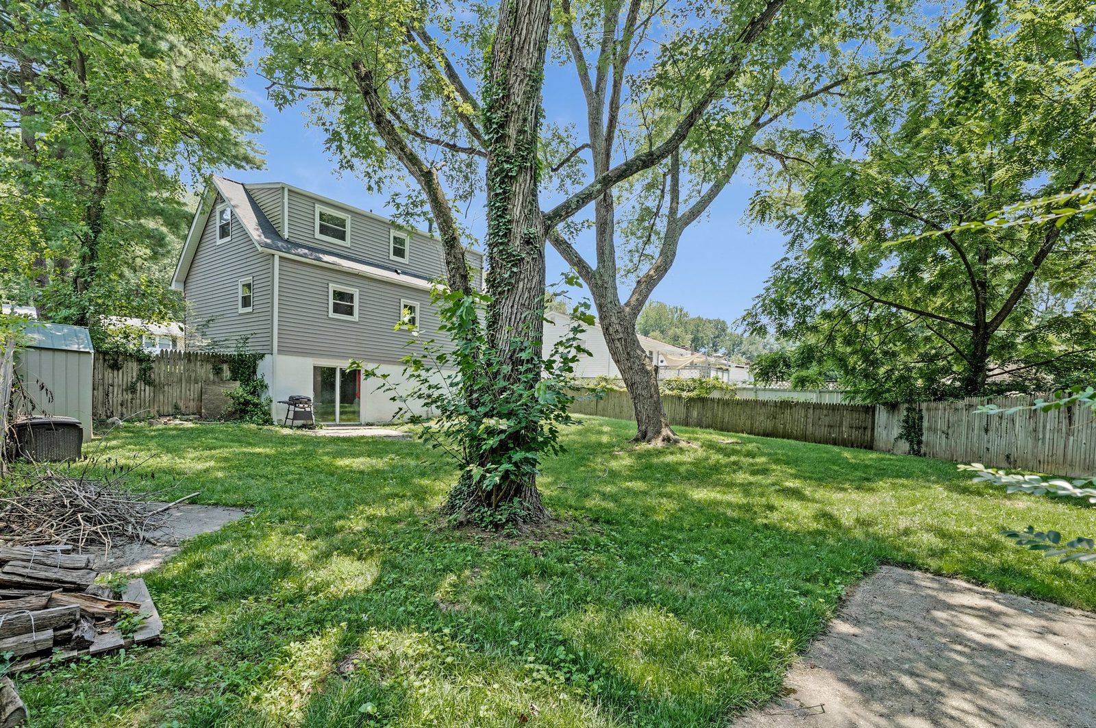Rear exterior with grey siding, dormer window and fenced lawn