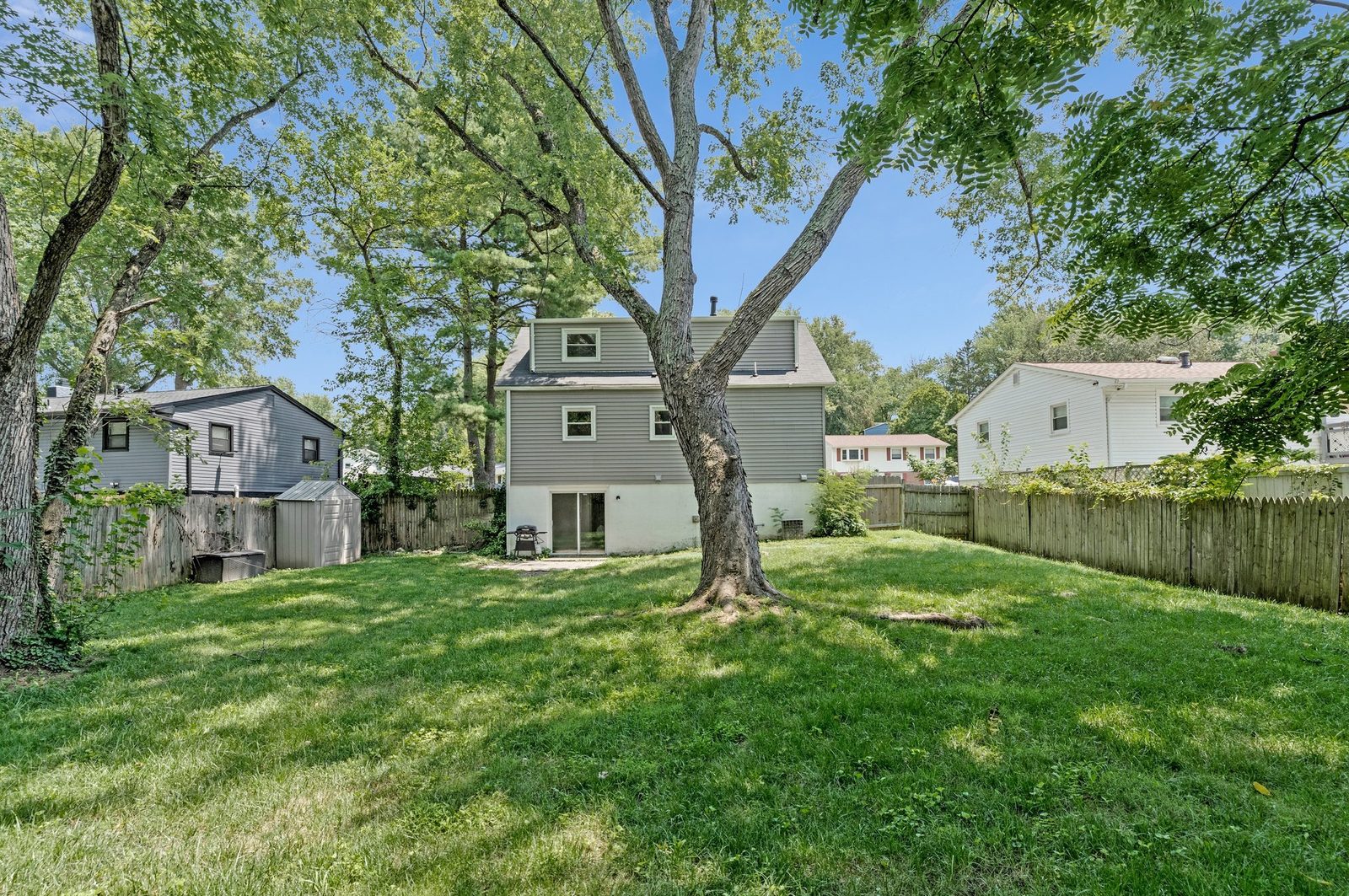 Rear elevation with grey siding and large fenced back lawn