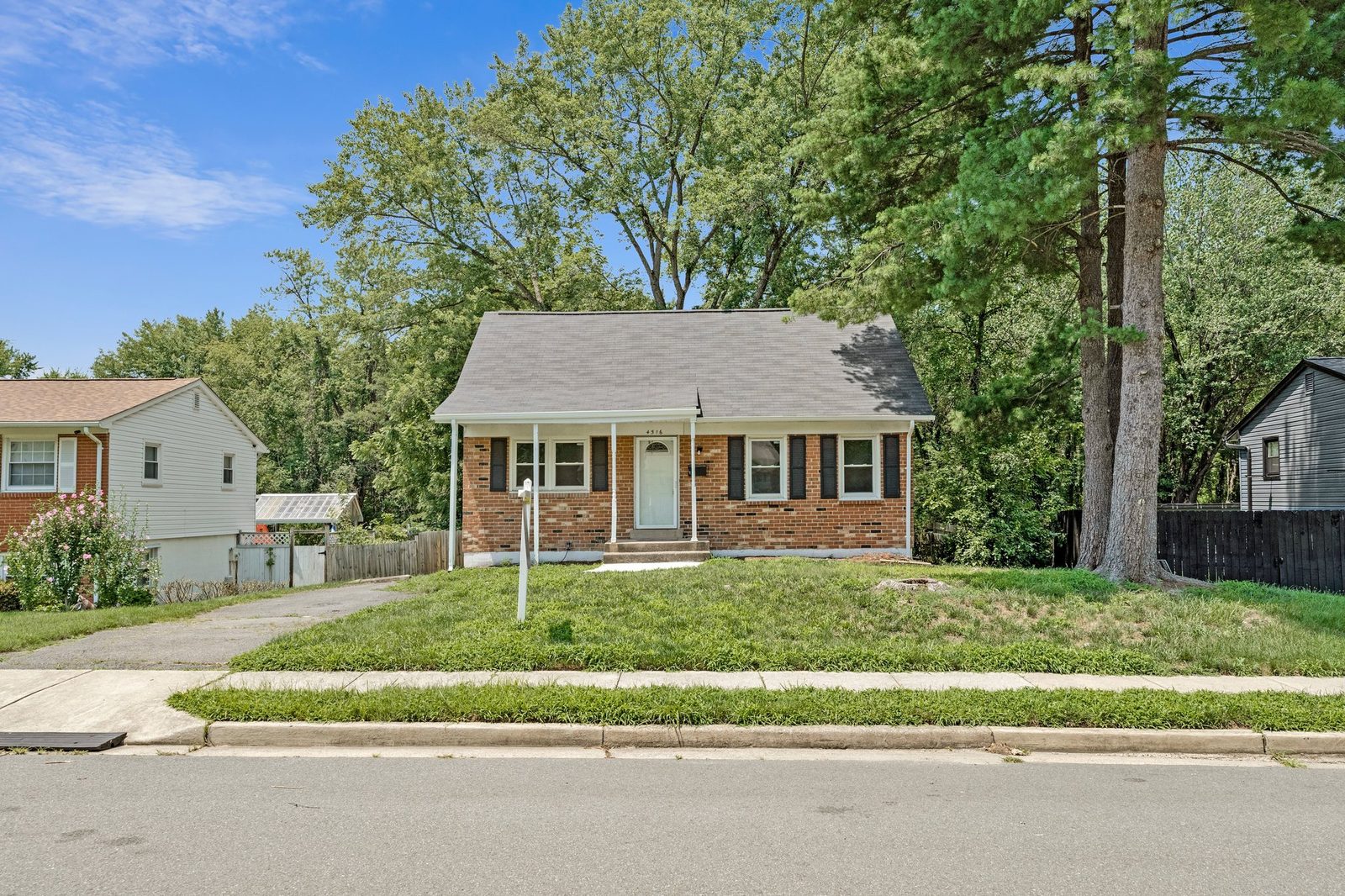 Front elevation of brick home with covered porch and black shutters