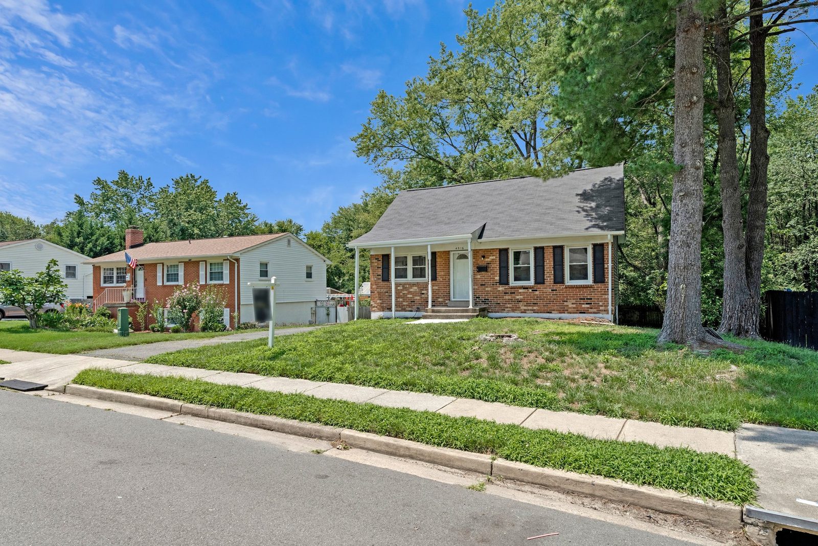 Street view of brick home with front lawn and sidewalk