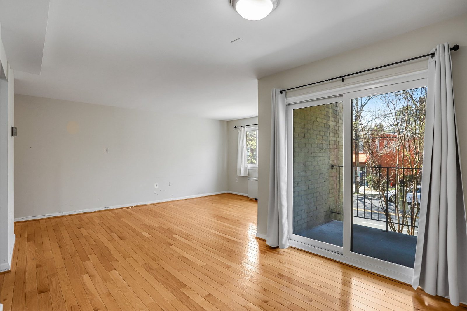Bright living room with hardwood floors and sliding door to balcony