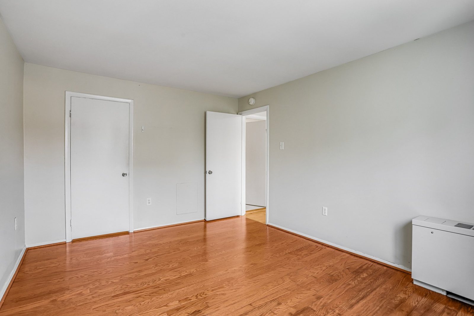 Empty room with oak floors, closet door and doorway to hallway