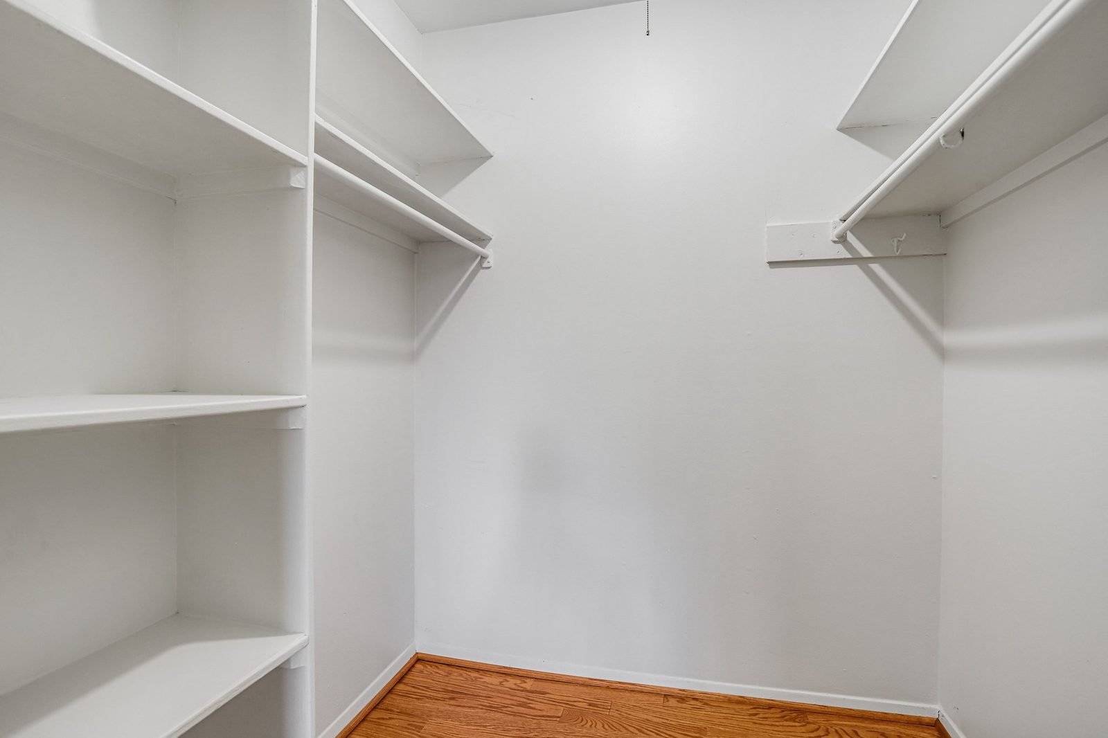 Walk-in closet with white built-in shelving and hanging rods