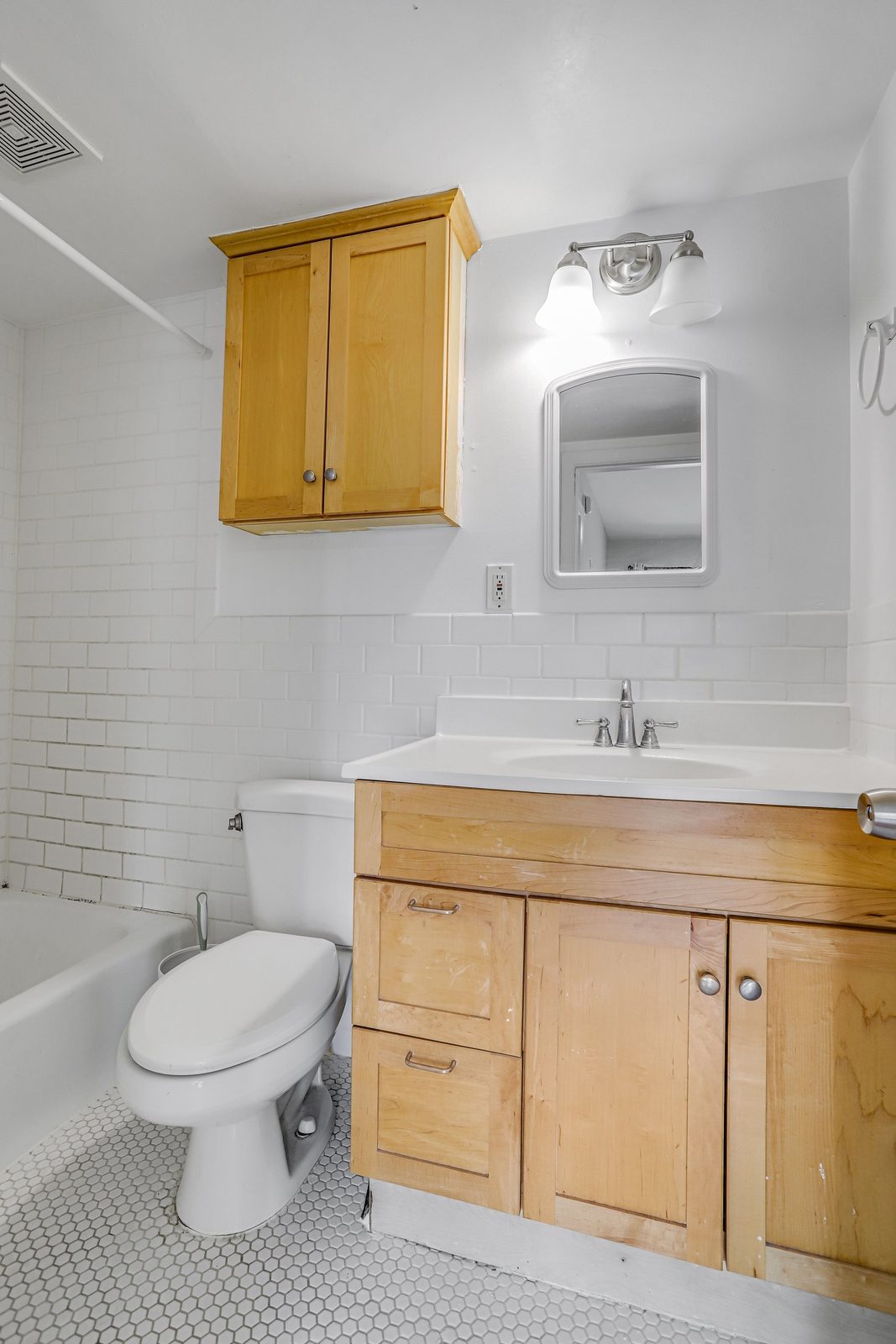 Bathroom with hexagonal tile floor, tub and wood vanity