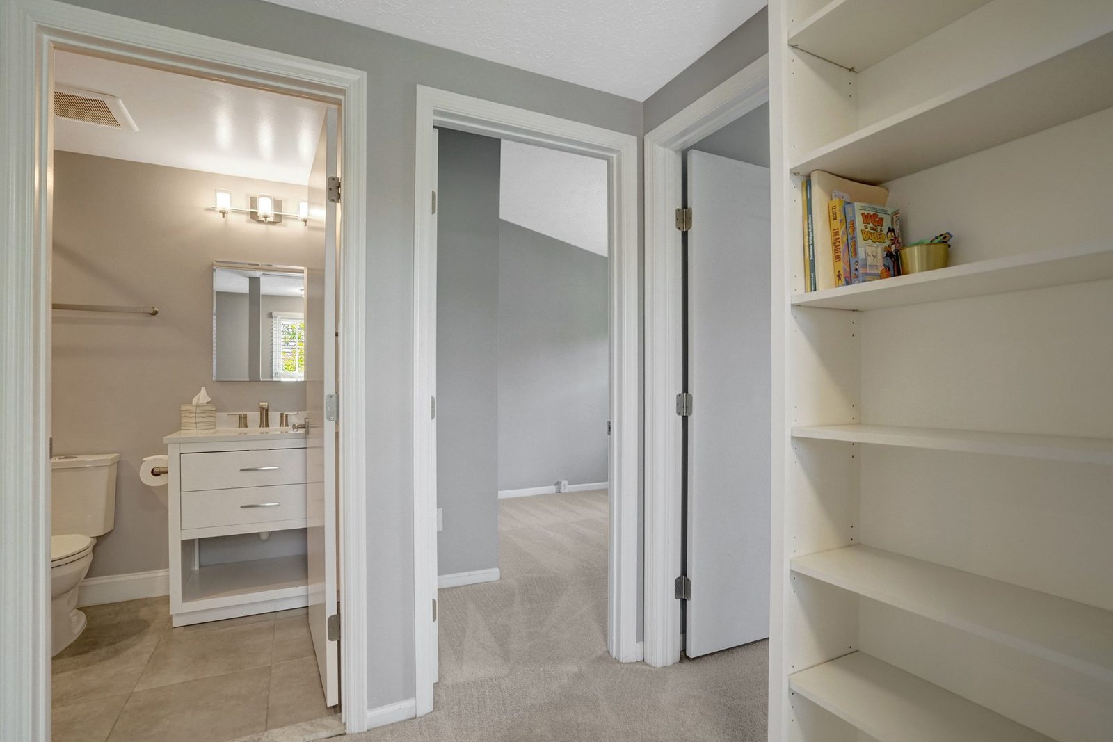 Carpeted upstairs hall with built-in shelving and bathroom doorway