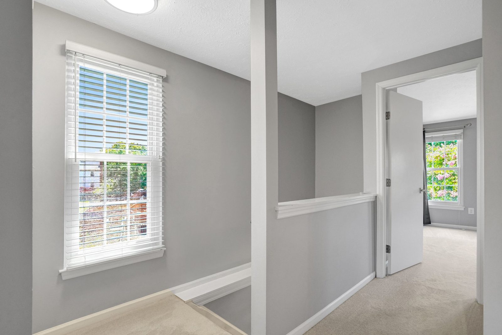 Upstairs landing with tall window and half-wall stair railing