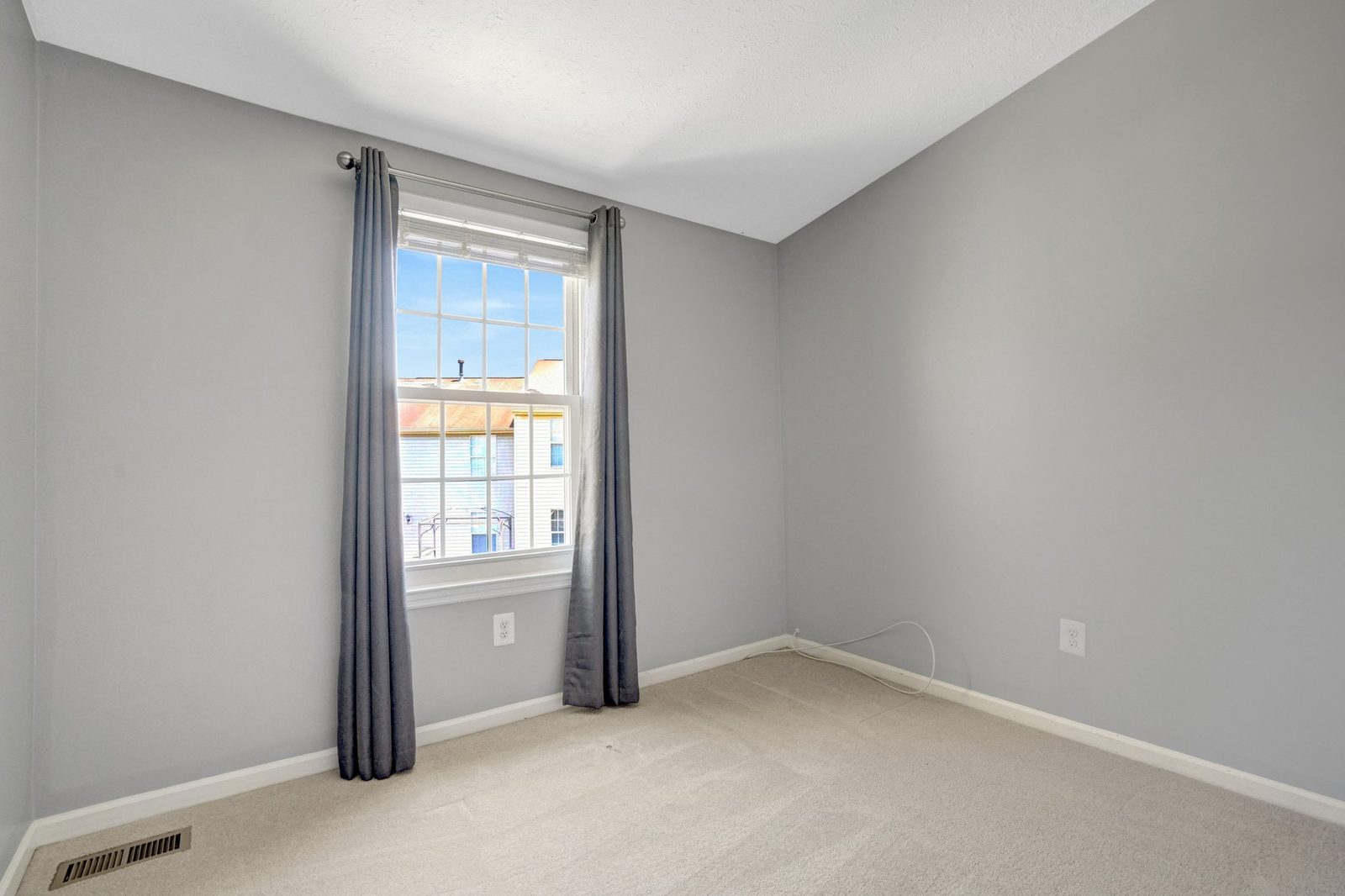 Carpeted room with curtained window and grey painted walls