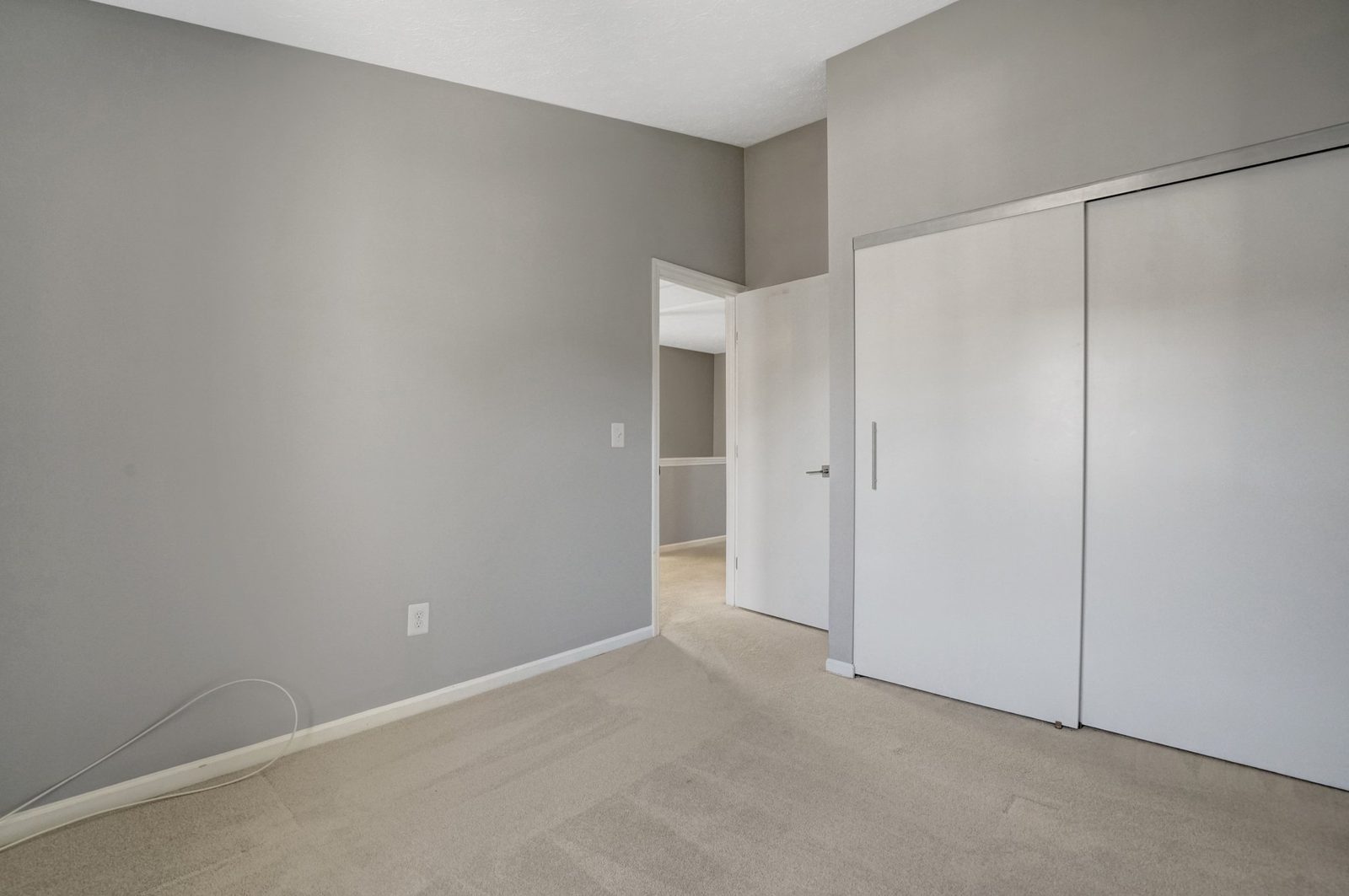 Carpeted room with wide sliding closet doors and open doorway