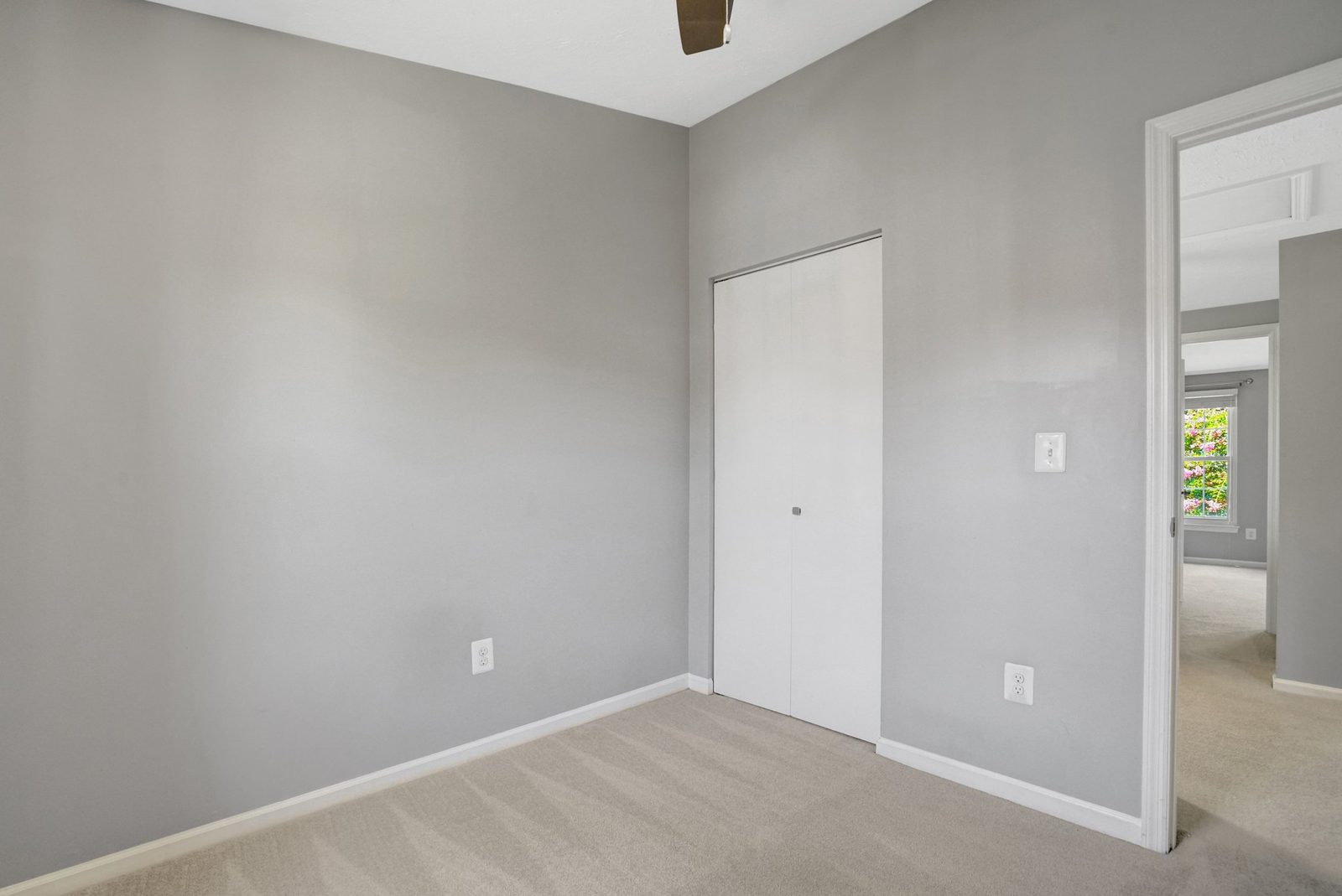 Carpeted room with bifold closet doors and hallway doorway