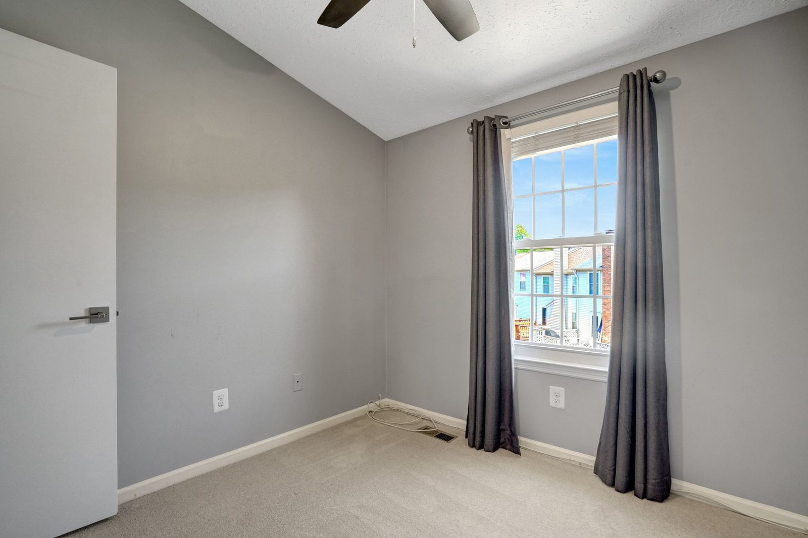 Carpeted corner room with ceiling fan and single window