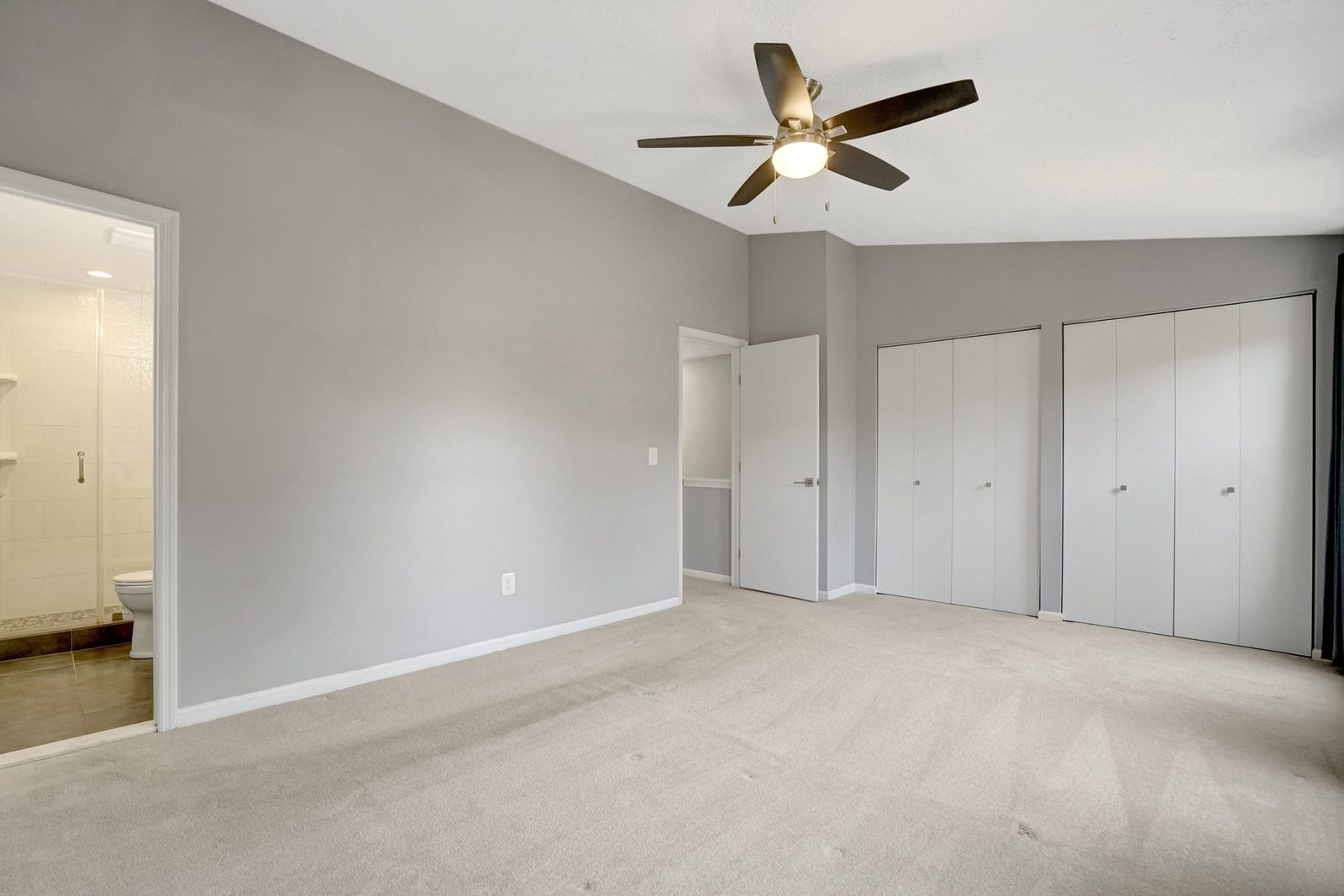 Carpeted room with double closets and adjoining tiled bathroom