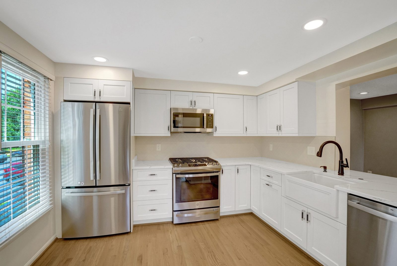 Kitchen with white shaker cabinets, stainless appliances and apron sink