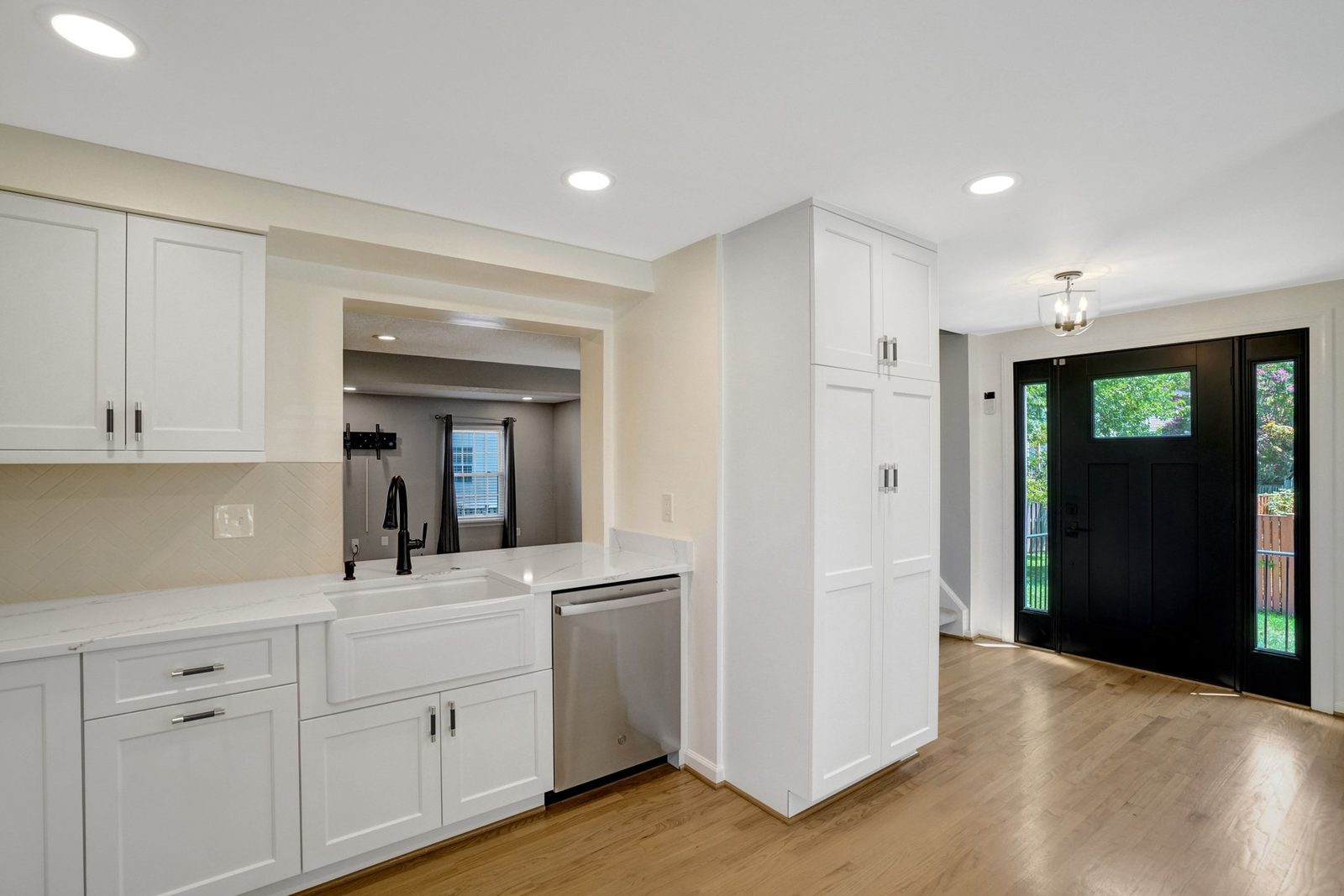 Kitchen with apron-front sink and pantry cabinets opening to the front entry