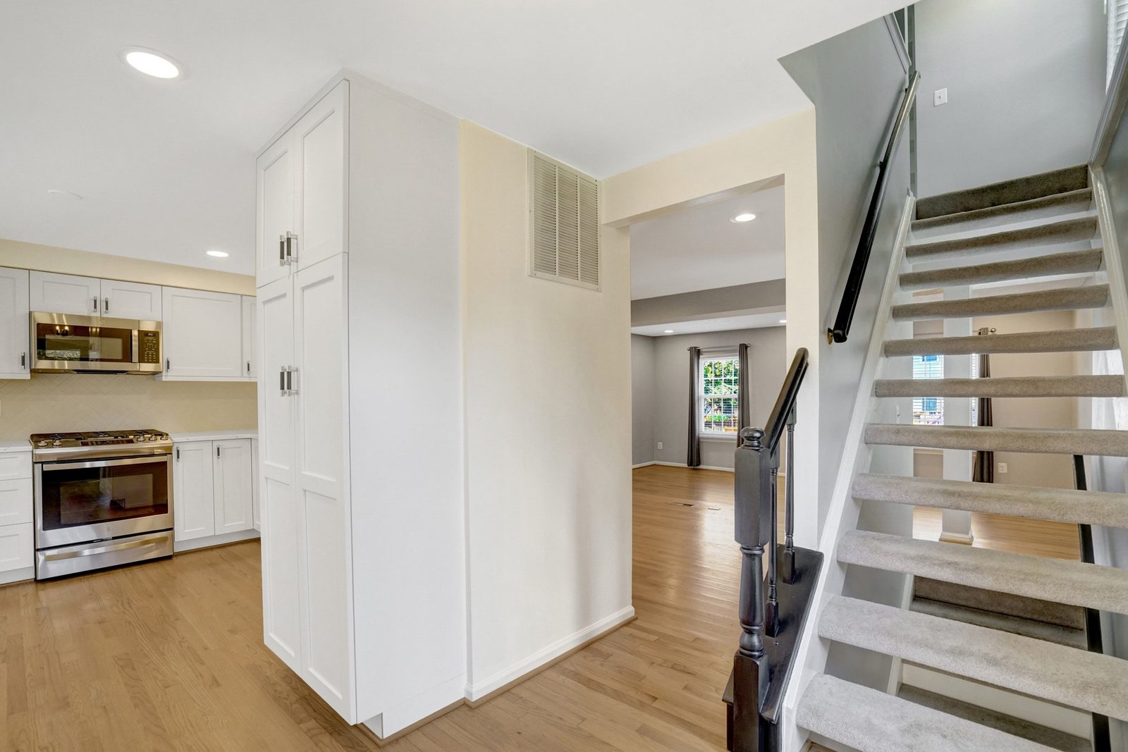 Kitchen with stainless range and tall pantry cabinets beside carpeted staircase