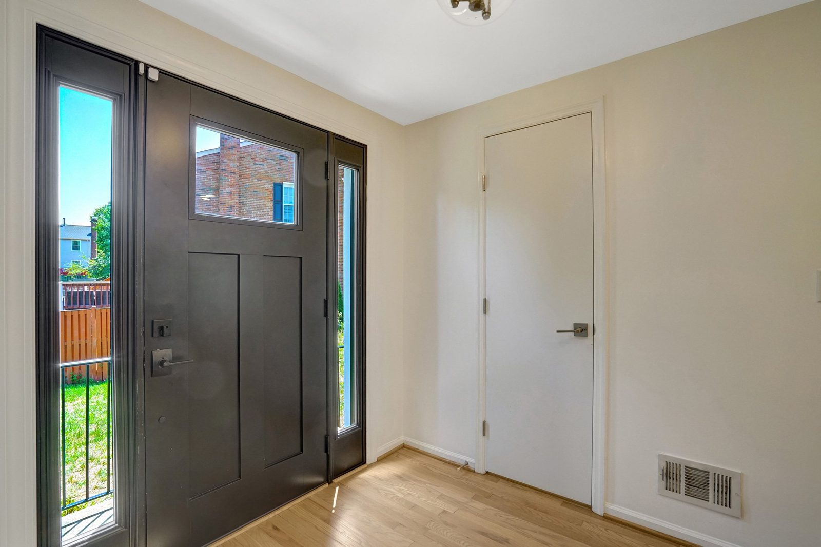 Entry vestibule with hardwood floor, black front door and closet door