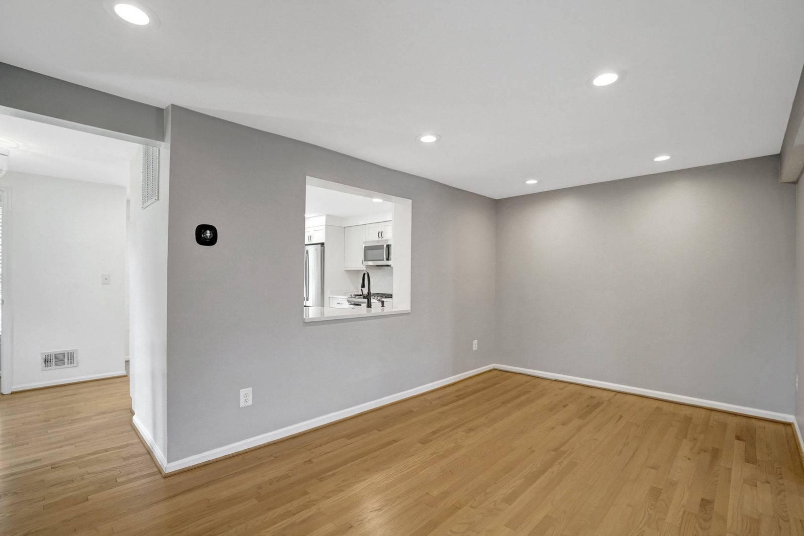 Gray-walled room with hardwood floors and pass-through window to the kitchen