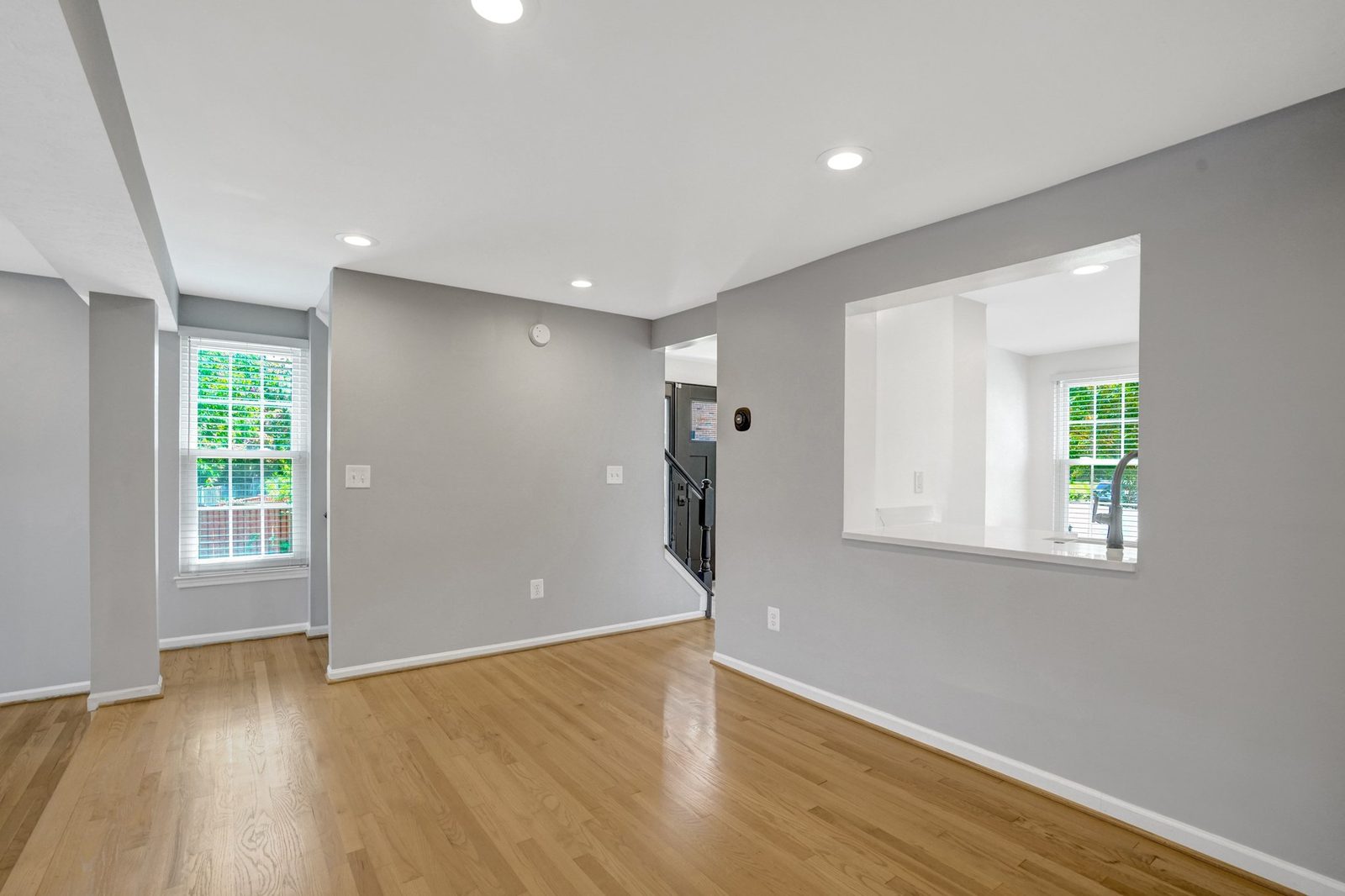 Hardwood room with kitchen pass-through window and view to the staircase