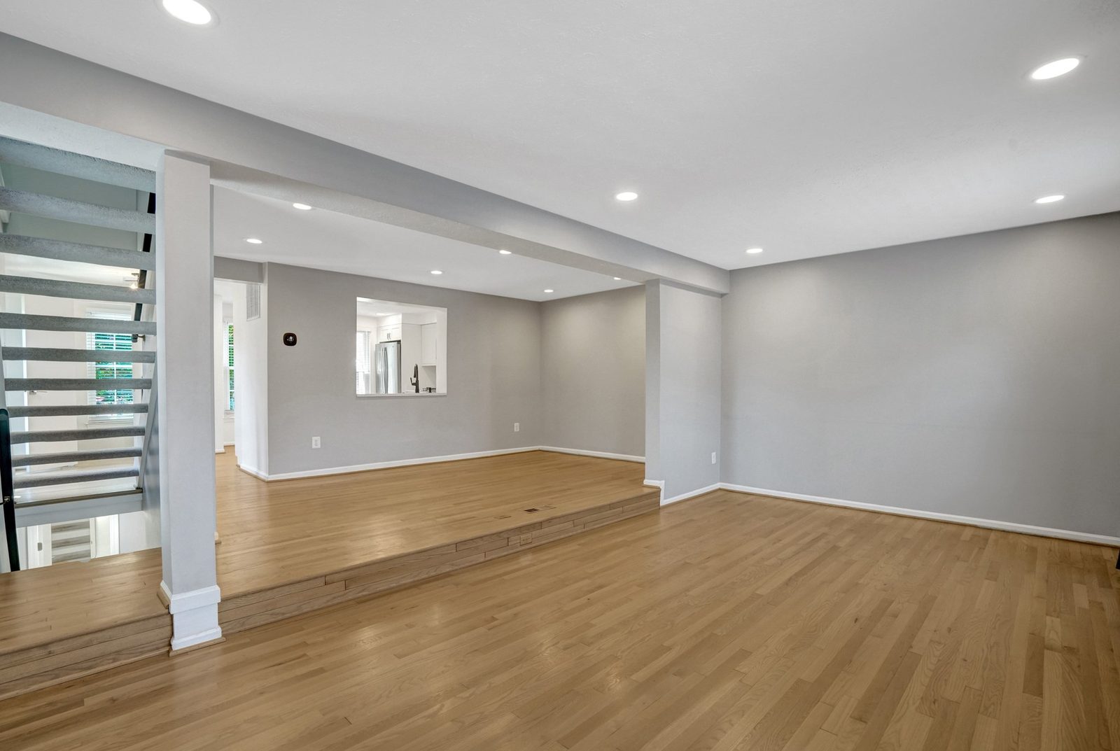 Open lower-level living area with hardwood floors and step to landing