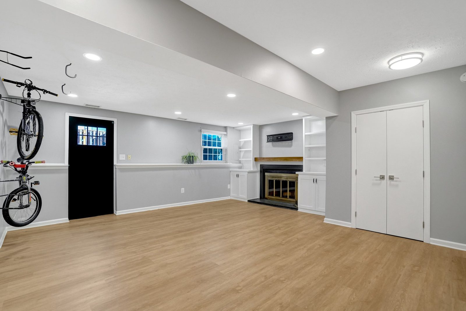 Lower-level room with fireplace, white built-in shelving and double closet