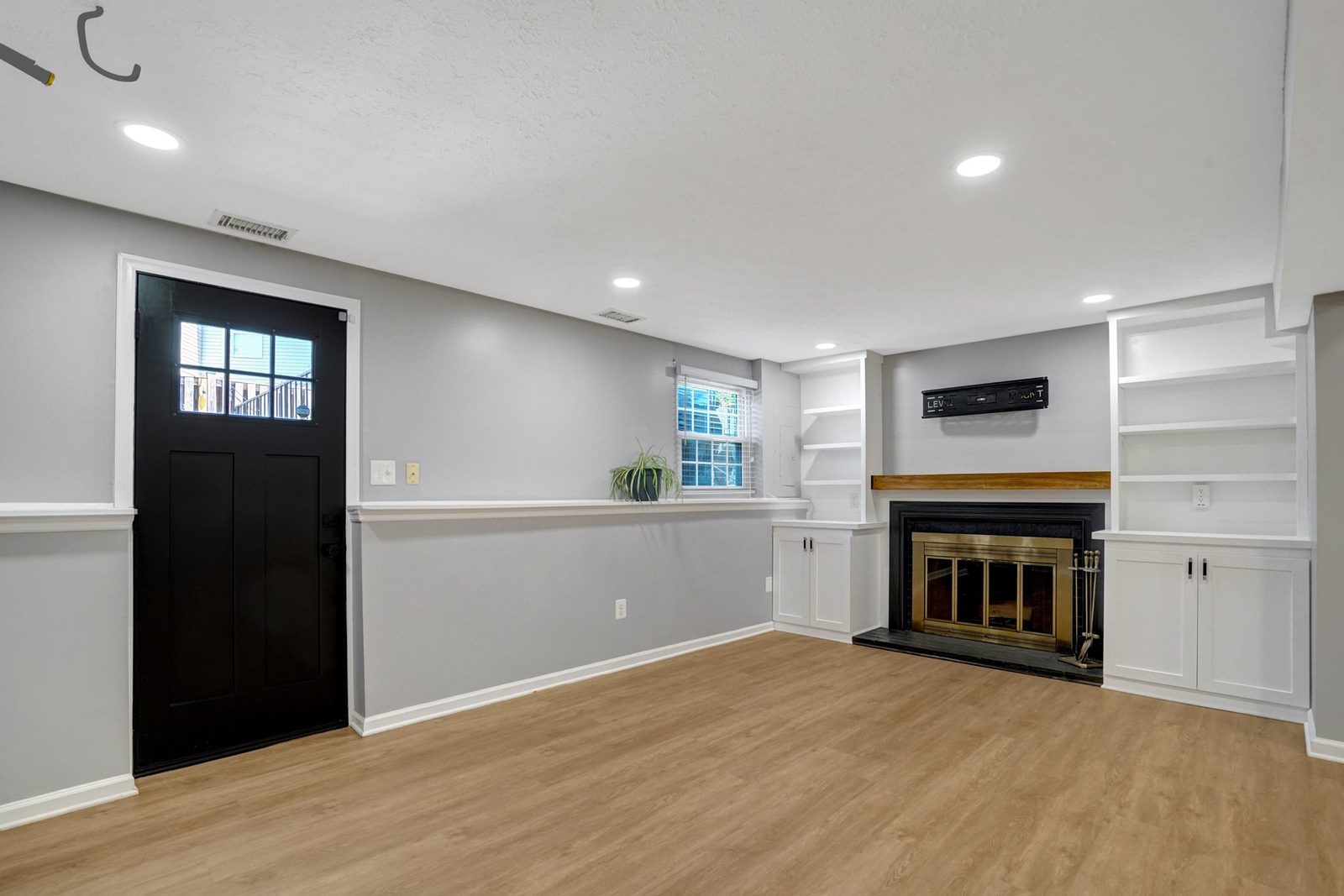 Open lower level with brass-front fireplace and glass-panel exterior door