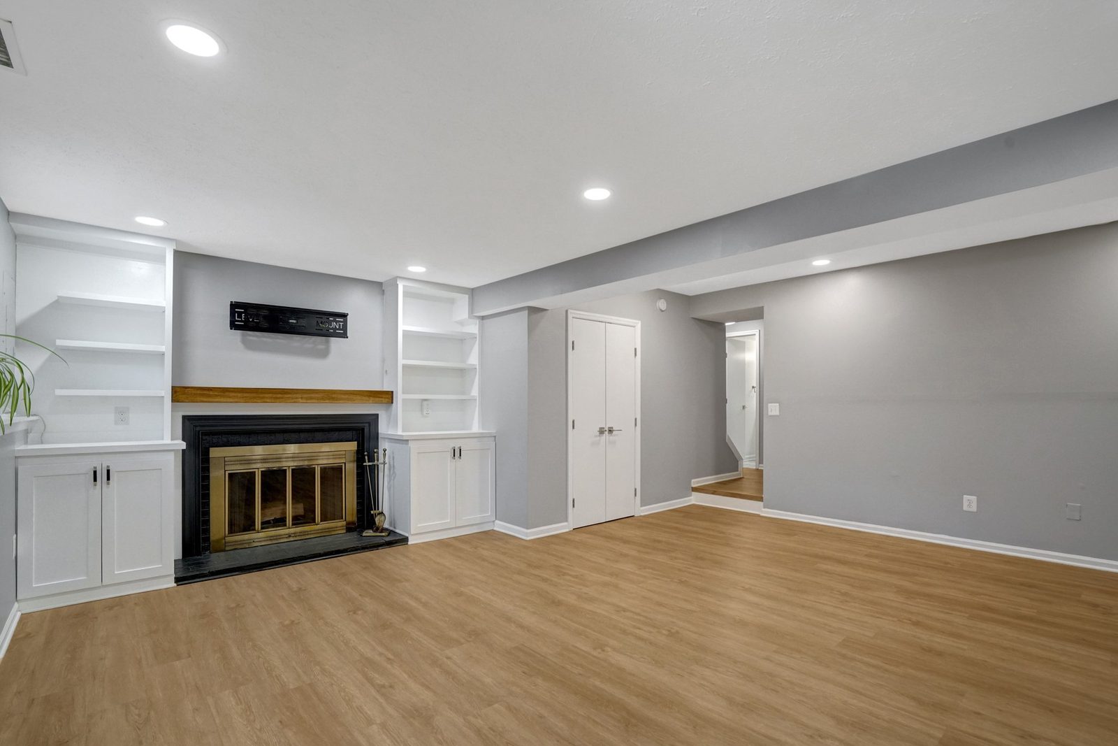 Fireplace with wood mantel flanked by white built-in cabinets and shelves