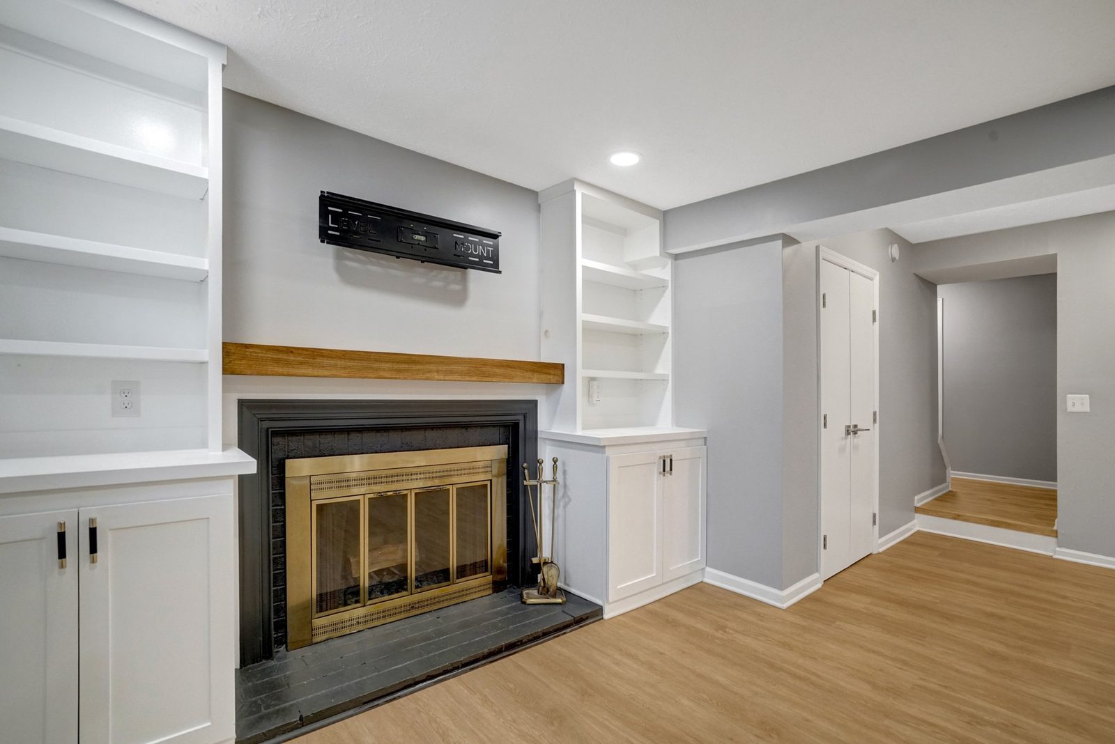 Brass-door fireplace with wood mantel and adjacent built-in cabinetry