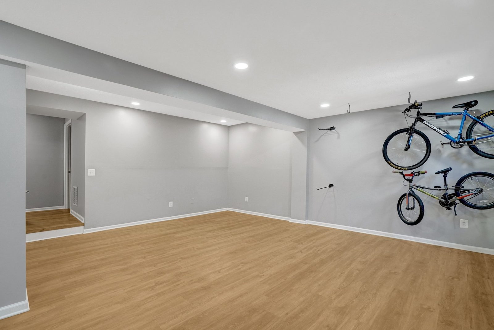 Empty lower-level room with gray walls and wood-look plank flooring