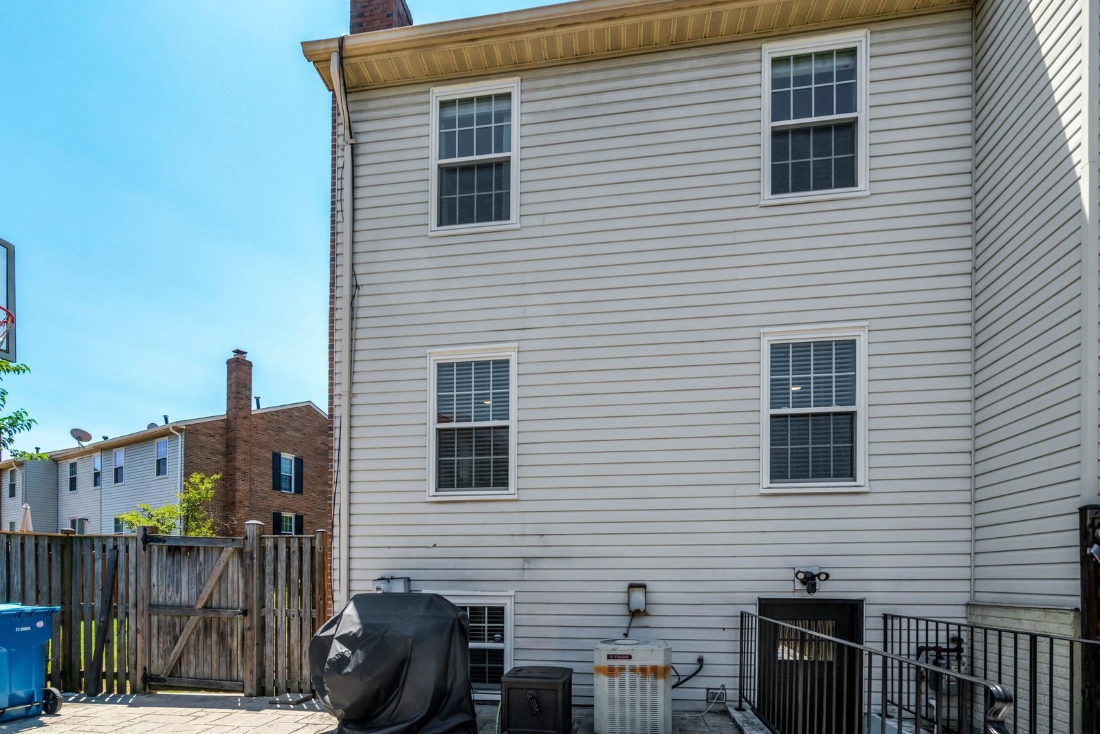 Rear exterior with vinyl siding, wood privacy fence and paved patio