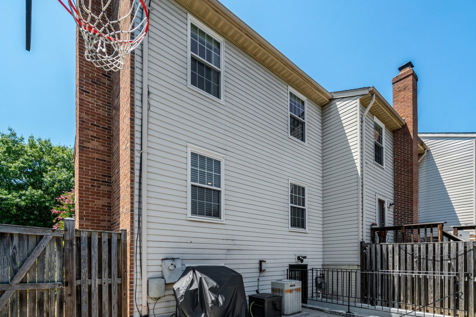 Side and rear exterior with brick chimney and fenced paved patio