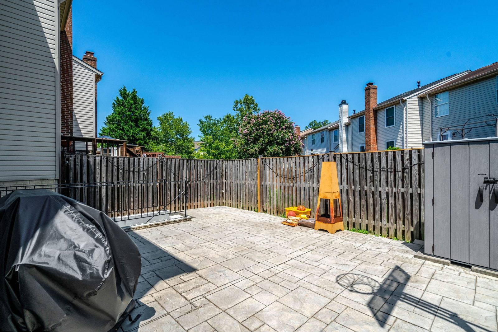 Stamped concrete patio enclosed by wood privacy fence with storage shed