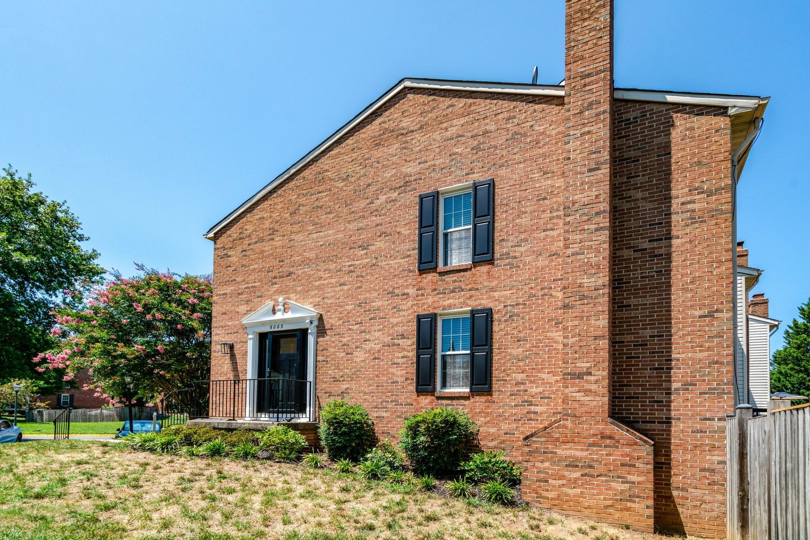 Brick end-unit townhouse with black shutters and pedimented front entry