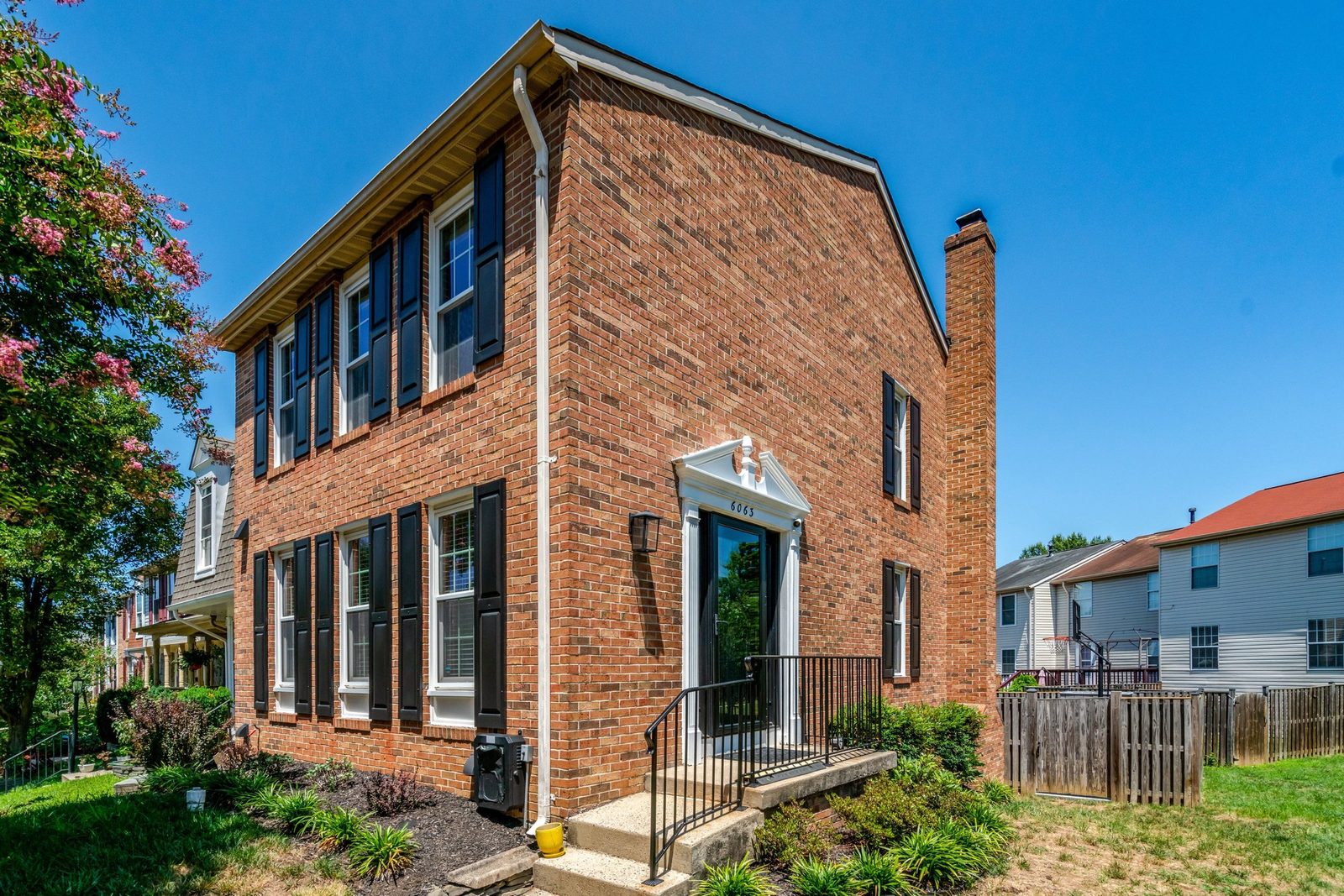 Angled front view of brick townhouse with iron railing entry steps