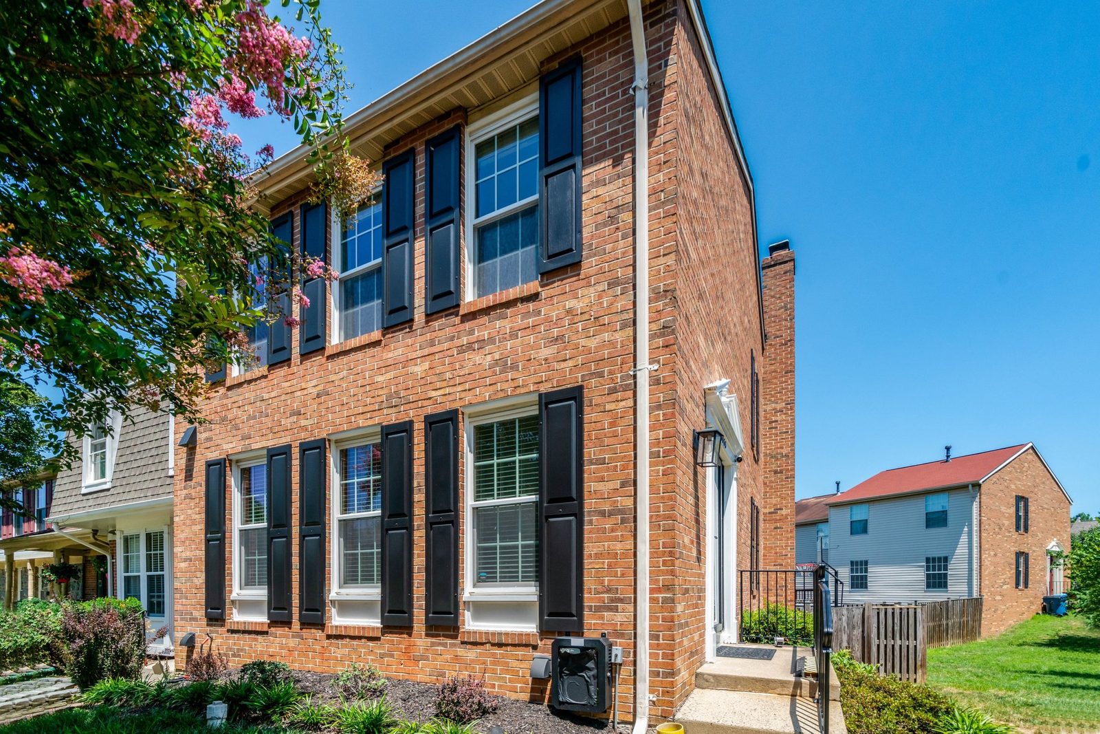 Brick facade with white-trimmed windows, black shutters and side entry