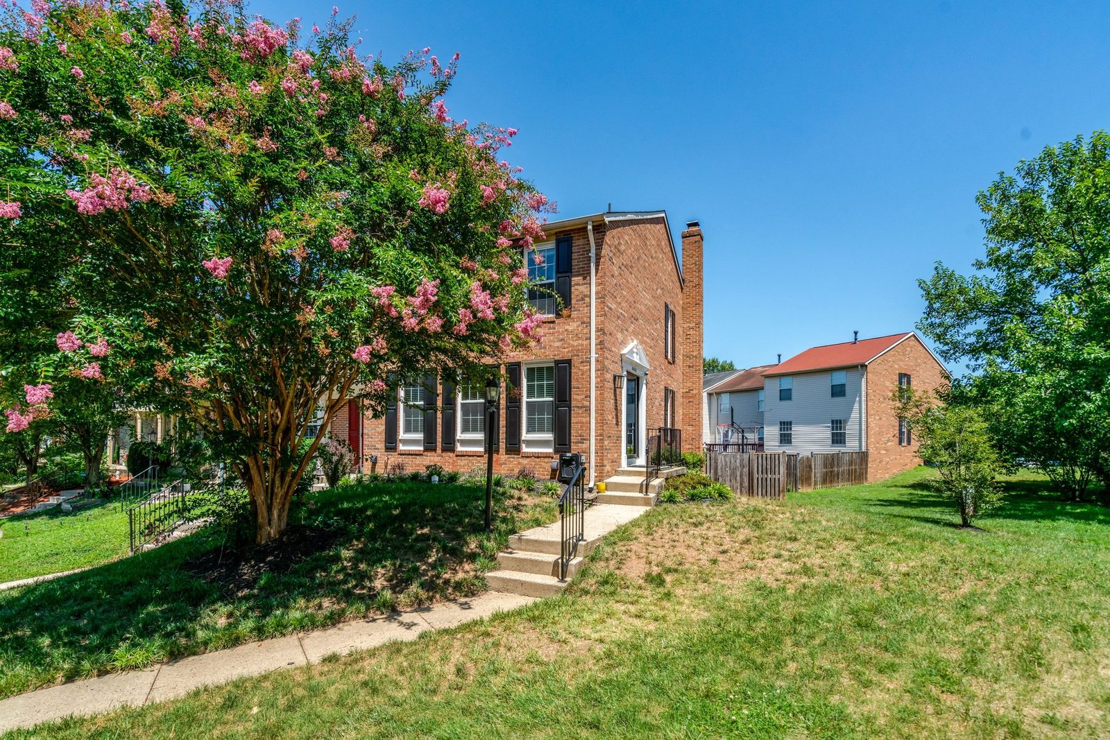 Front walkway and steps leading to brick townhouse entry across lawn