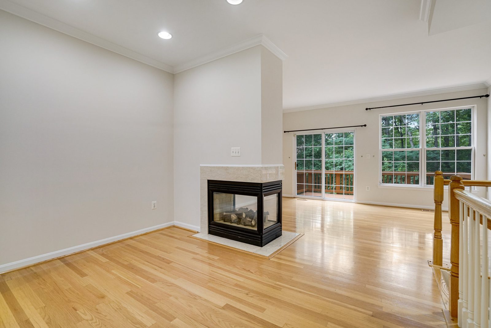 Living room with hardwood floors, three-sided gas fireplace and deck slider