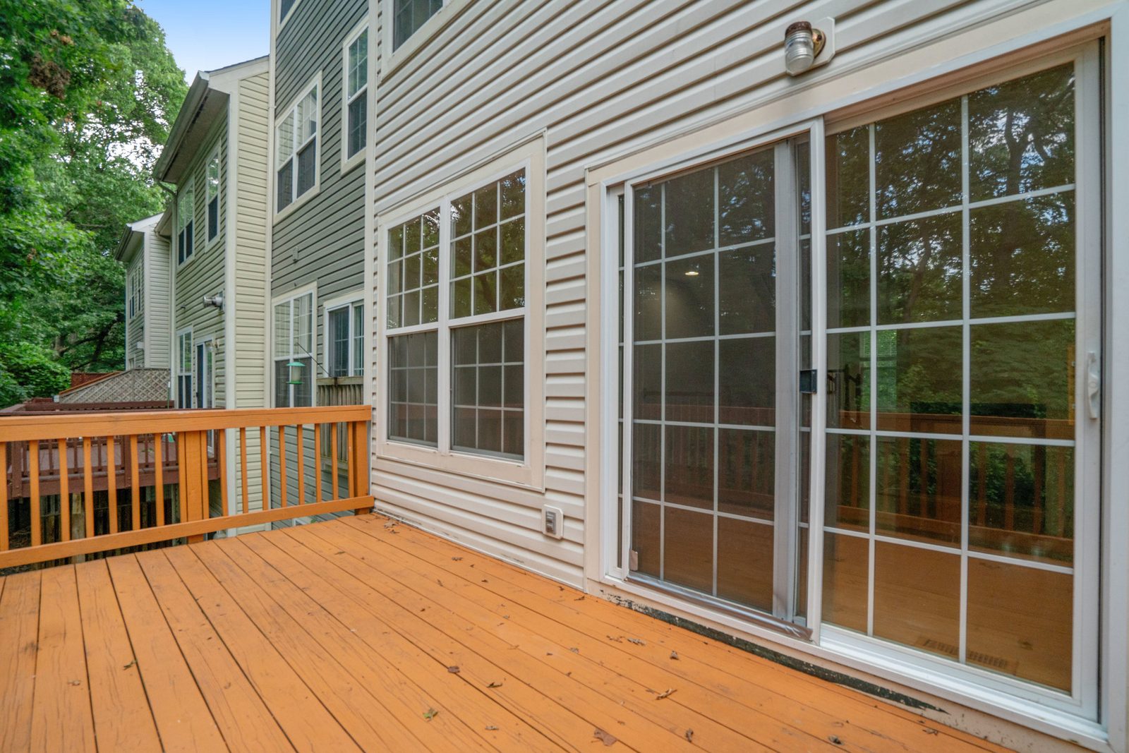 Deck along vinyl-sided rear elevation with sliding glass door