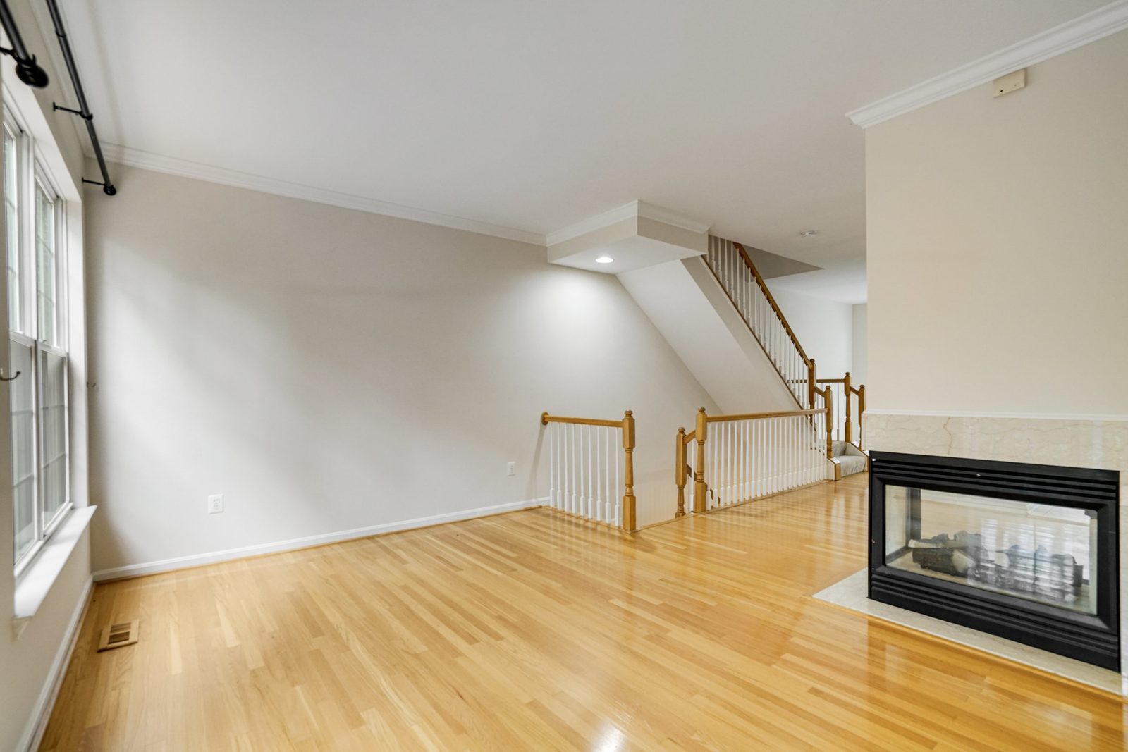 Hardwood room with three-sided glass fireplace and open staircase